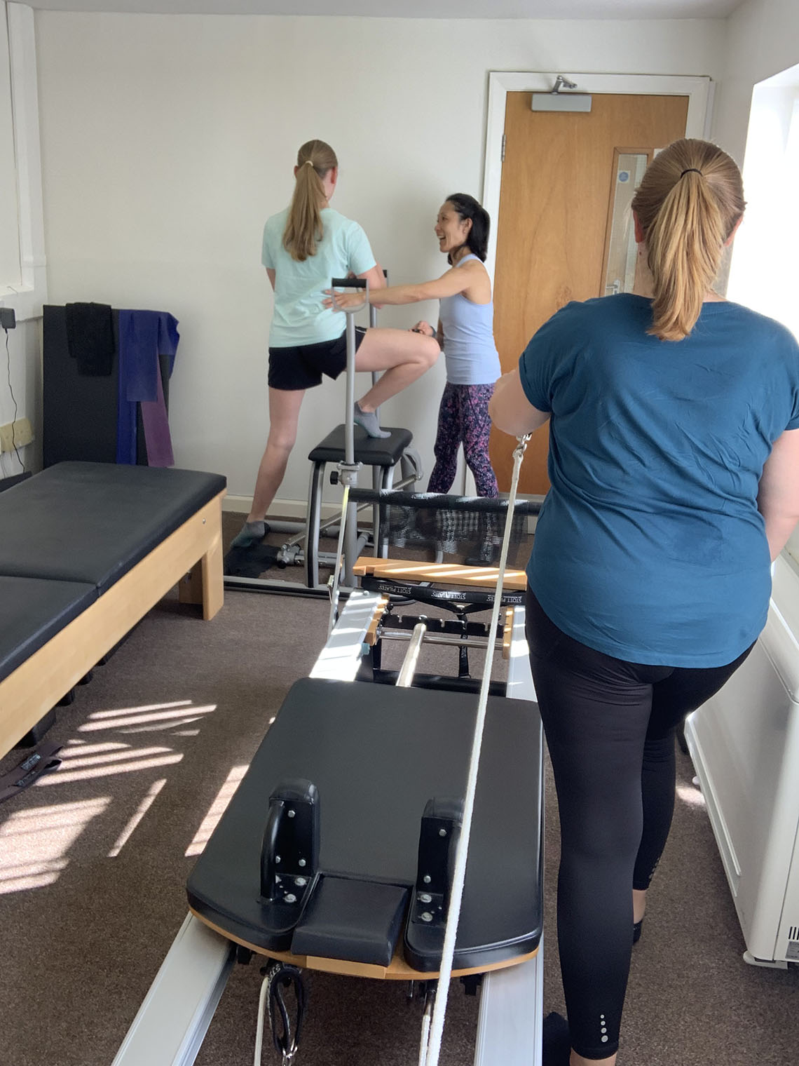 A picture of the pilates instructor with two clients